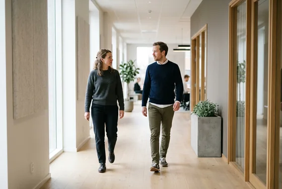 Two colleagues walking through a bright office corridor