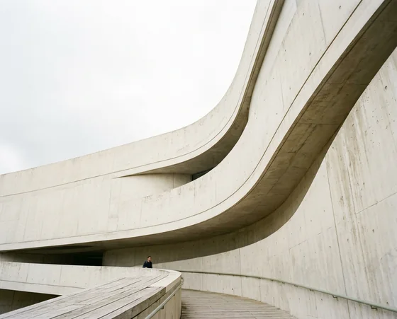 Curved pale concrete facade against an overcast sky
